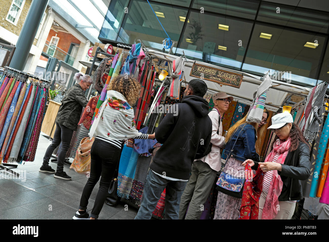 People shopping for scarves at a scarf stall 'Kashimi Scarves' in Spitalfields Market near Brick Lane in East London E1 UK  KATHY DEWITT Stock Photo