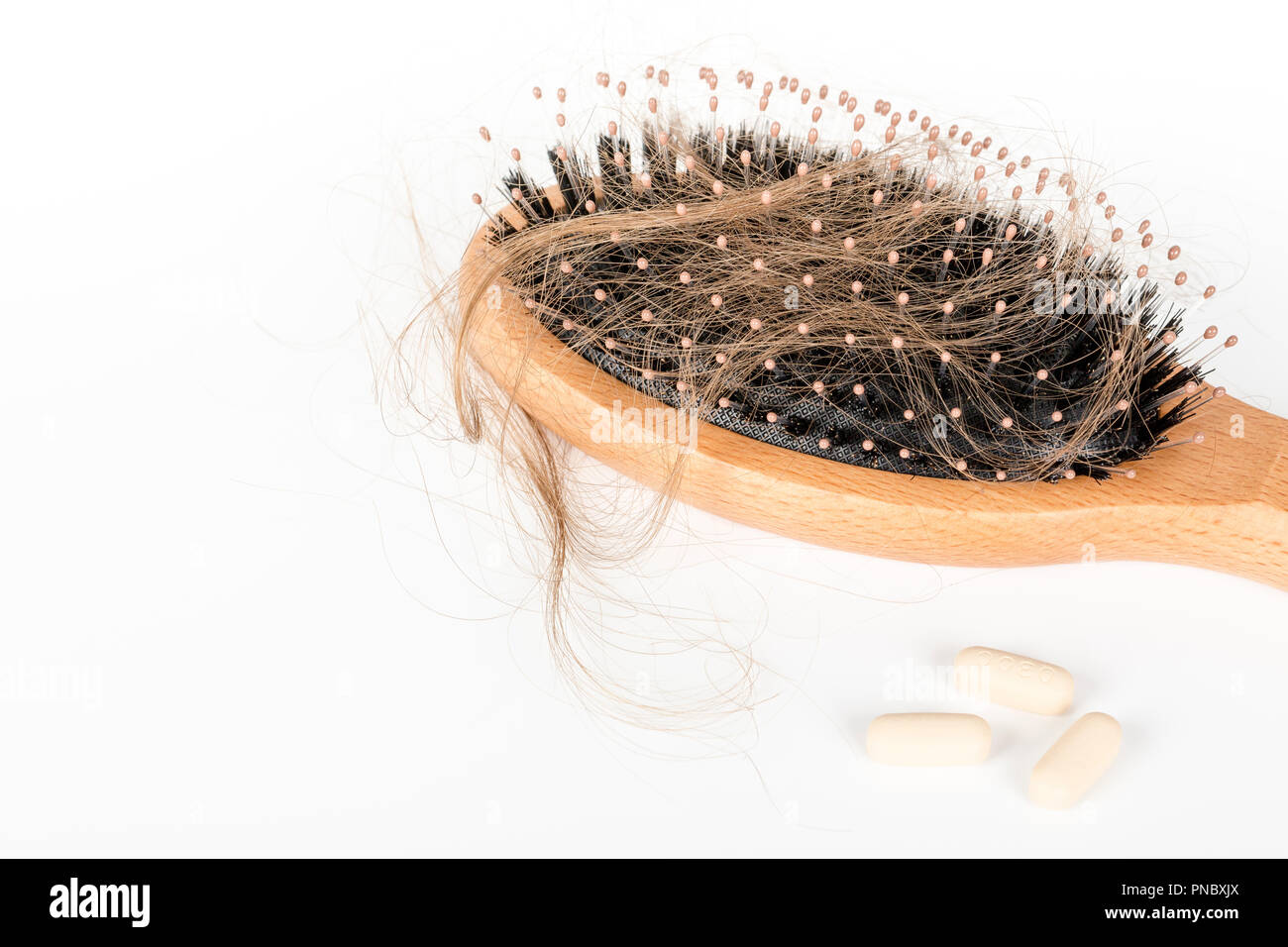 Wood hairbrush on white background. Closeup with long brown hair and