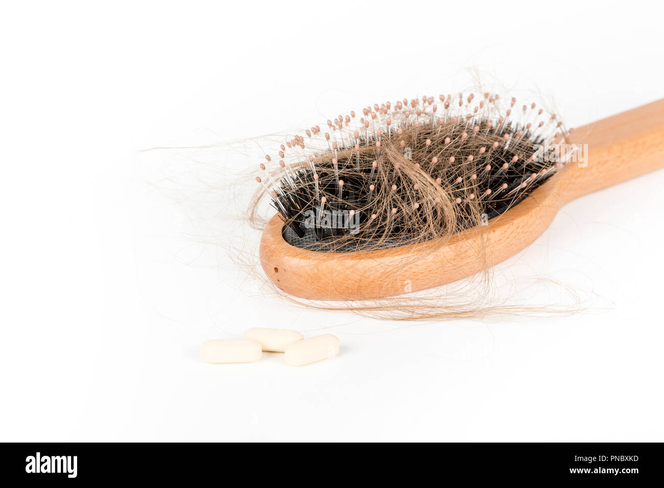 Wood hairbrush on white background. Closeup with long brown hair and