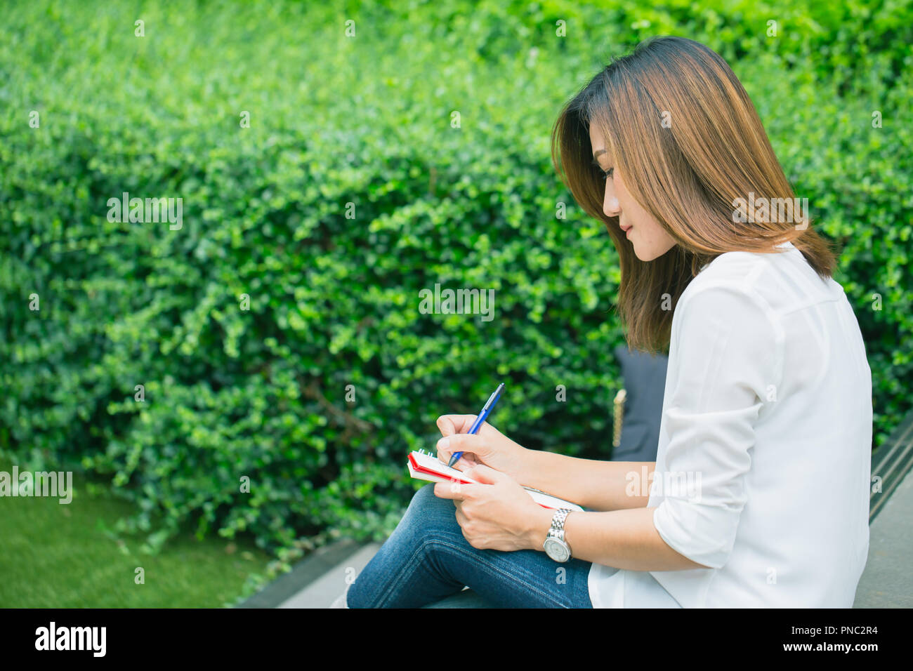 working women writing at park, working outdoor women work business job writer write text in notebook. Stock Photo