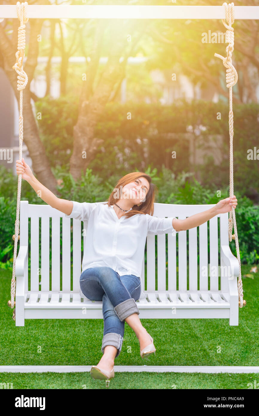 single asian women adult relax sitting at swing in the park. enjoy healthy good life concept. Stock Photo