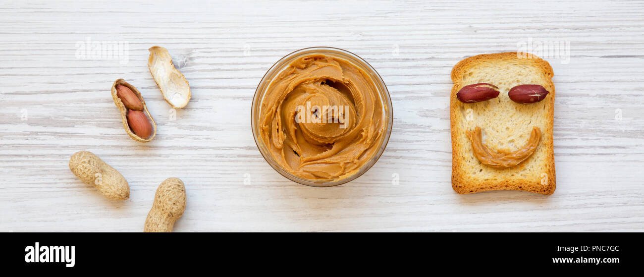 Creative pattern made of toast, peanut butter and peanuts in shells, overhead view. Flat lay, from above. Stock Photo