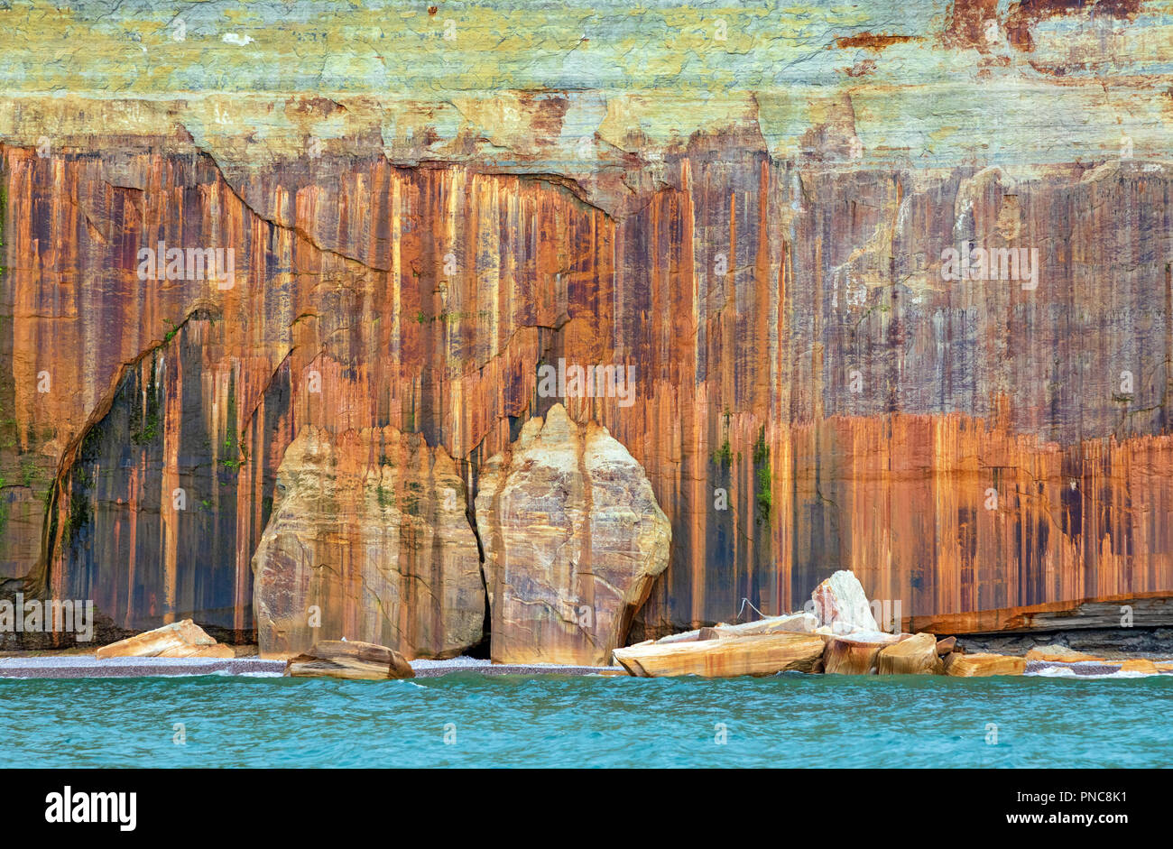 Mineral streaked cliff wall at Pictured Rocks National Lakeshore in the Upper Peninsula of Michigan with Lake Superior in the foreground Stock Photo