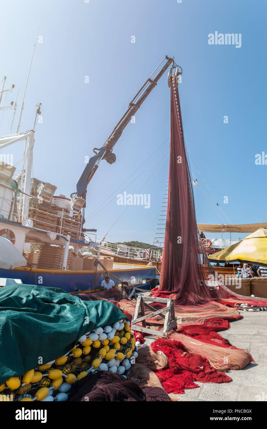 Multi-colored fishing nets raises the crane on the pier by the sea. Fish  production. Repair of networks Stock Photo - Alamy