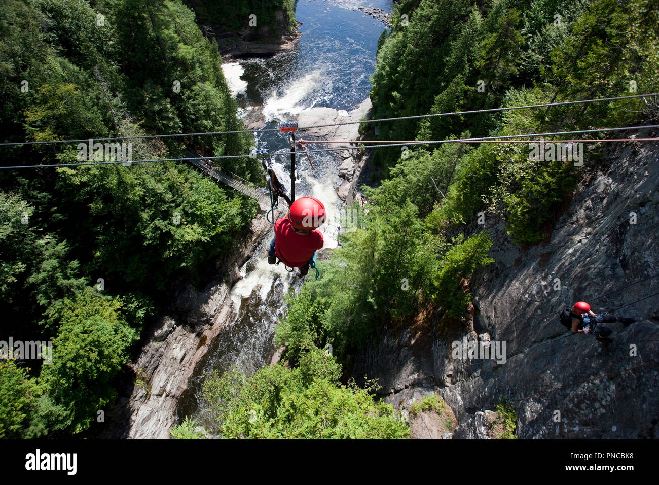 North America, Canada, Quebec, Beaupre, Canyon Ste-Anne,  boy on zip line watching woman rock climber Stock Photo