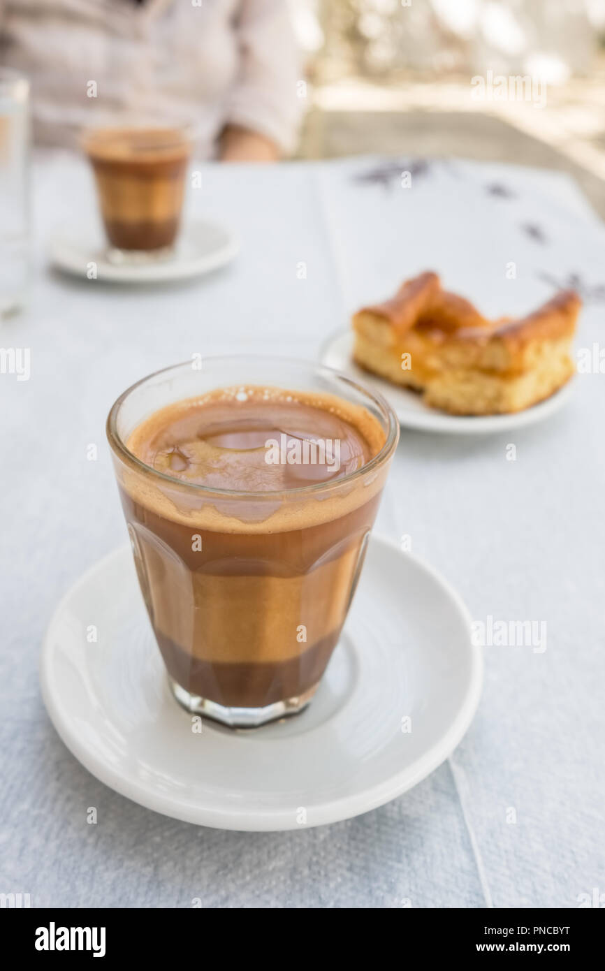 Traditional greek coffee served with a piece of pie in outdoor cafe in Greece Stock Photo