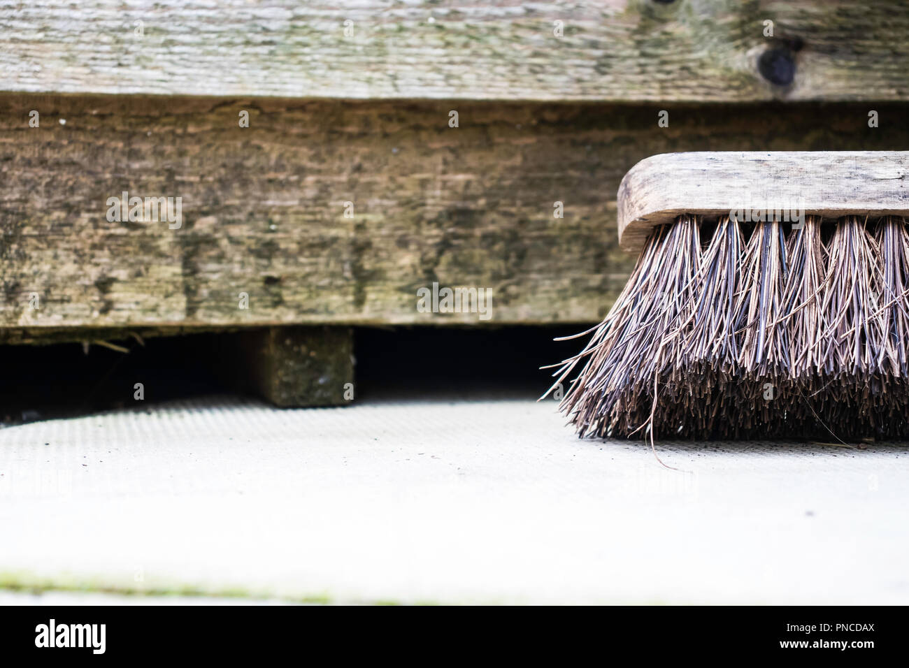 Close up of garden broom leaning against wooden shed Stock Photo