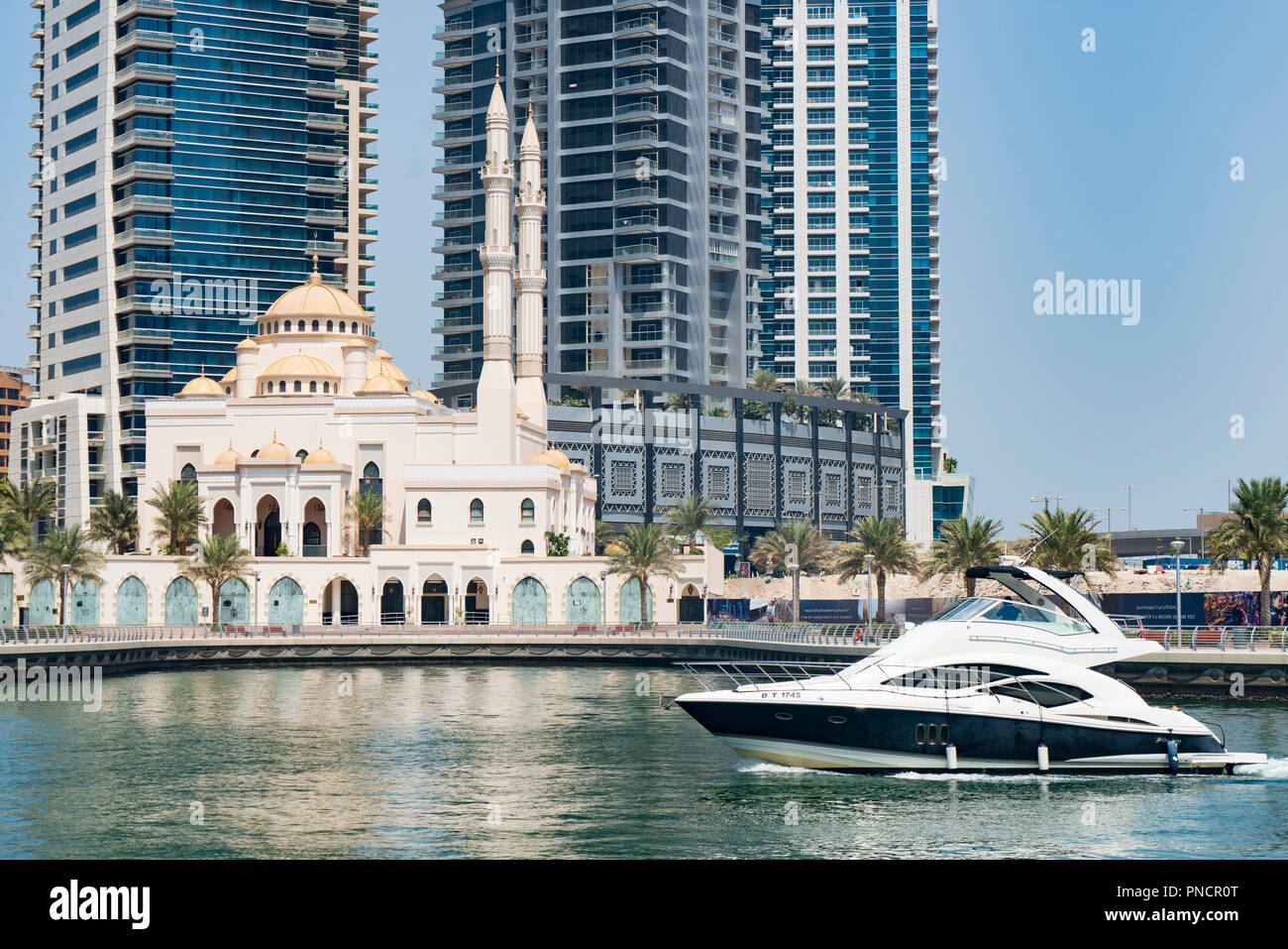 Contrast between motor boat and new mosque at Dubai Marina district in UAE Stock Photo