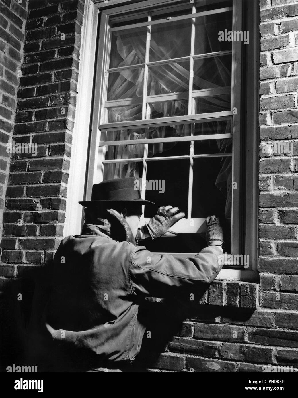 1950s THIEF MAN WEARING HAT GLOVES JACKET BREAKING INTO BRICK HOUSE OPENING  WINDOW NIGHTTIME - c6207 HAR001 HARS MALES RISK ROBBER STEALING B&W WINDOWS THIEF  ROBBERY DISASTER PROTECTION EXTERIOR LOW ANGLE OPPORTUNITY