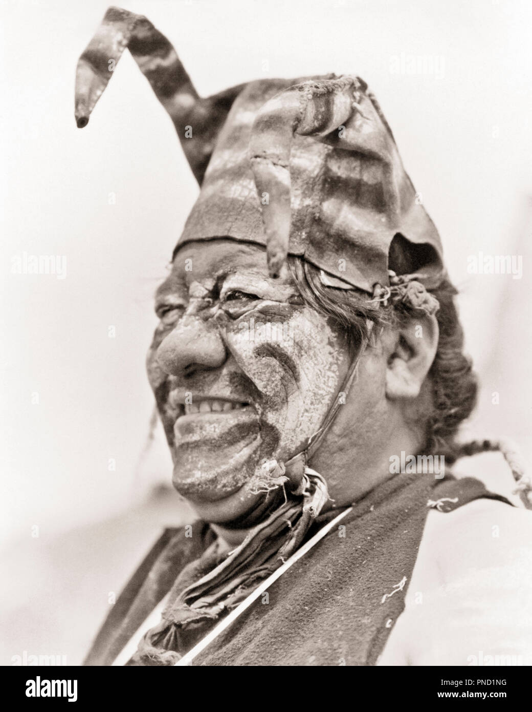 1930s HEAD CLOWN COCHARE KOSHARE IN COSTUME MAKEUP SAN ILDEFONSO PUEBLO NEW MEXICO  - i1389 HAR001 HARS MIDDLE-AGED B&W NORTH AMERICA MIDDLE-AGED MAN HAPPINESS HEAD AND SHOULDERS CHEERFUL RELIGIOUS LEADERSHIP PRIDE SACRED SMILES JESTER JOYFUL NATIVE AMERICAN PUEBLO FACE PAINT FAITHFUL SAN ILDEFONSO FAITH NATIVE AMERICANS NEW MEXICO TRICKSTER BELIEF BLACK AND WHITE CEREMONIAL HAR001 ILDEFONSO INDIGENOUS OLD FASHIONED Stock Photo