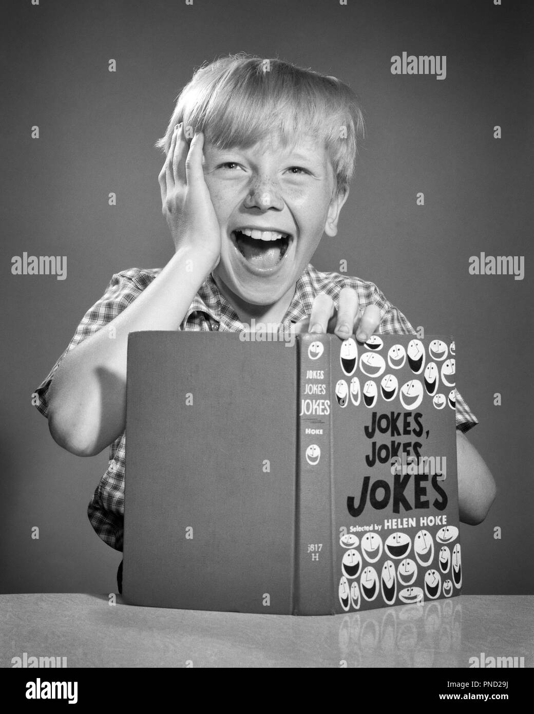 1950s BLOND BOY HOLDING HAND TO HEAD LAUGHING OUT LOUD LOOKING AT CAMERA READING BOOK FULL OF JOKES - j6441 DEB001 HARS JOY LIFESTYLE STUDIO SHOT HOME LIFE HALF-LENGTH INSPIRATION MALES FRECKLES ENTERTAINMENT EXPRESSIONS B&W EYE CONTACT SUCCESS HAPPINESS HEAD AND SHOULDERS CHEERFUL DISCOVERY YOUNG MAN EXCITEMENT TELLING COMEDIAN OF OPPORTUNITY SMILES CONCEPTUAL COMEDY IMAGINATION JOYFUL OVER THE TOP DEB001 GROWTH IDEAS JUVENILES RELAXATION RIOTOUS BLACK AND WHITE CAUCASIAN ETHNICITY JOKE OLD FASHIONED Stock Photo