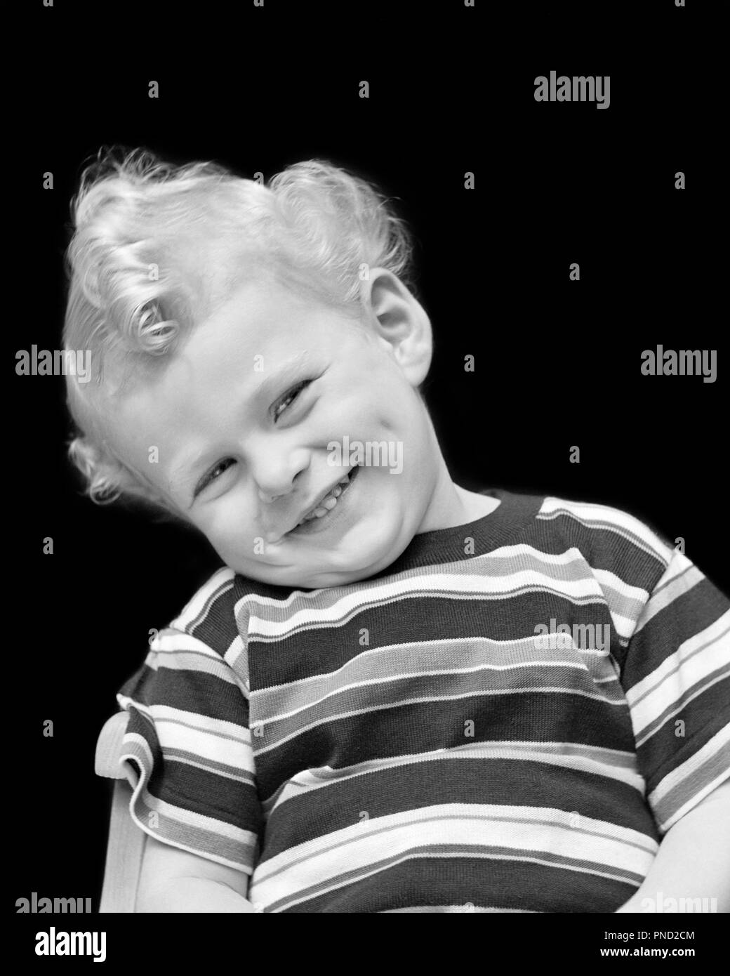 1940s PORTRAIT OF SMILING BOY WITH BLOND CURLY HAIR HEAD COCKED TO SIDE WEARING STRIPED TEE-SHIRT LOOKING AT CAMERA - j9582 HAR001 HARS PLEASED JOY LIFESTYLE STRIPED HEALTHINESS HOME LIFE HALF-LENGTH MALES EXPRESSIONS B&W EYE CONTACT ACTIVITY HAPPINESS PHYSICAL CHEERFUL STRENGTH CURLY OF SMILES FLEXIBILITY JOYFUL MUSCLES STYLISH CHARMING JUVENILES BLACK AND WHITE CAUCASIAN ETHNICITY HAR001 OLD FASHIONED Stock Photo