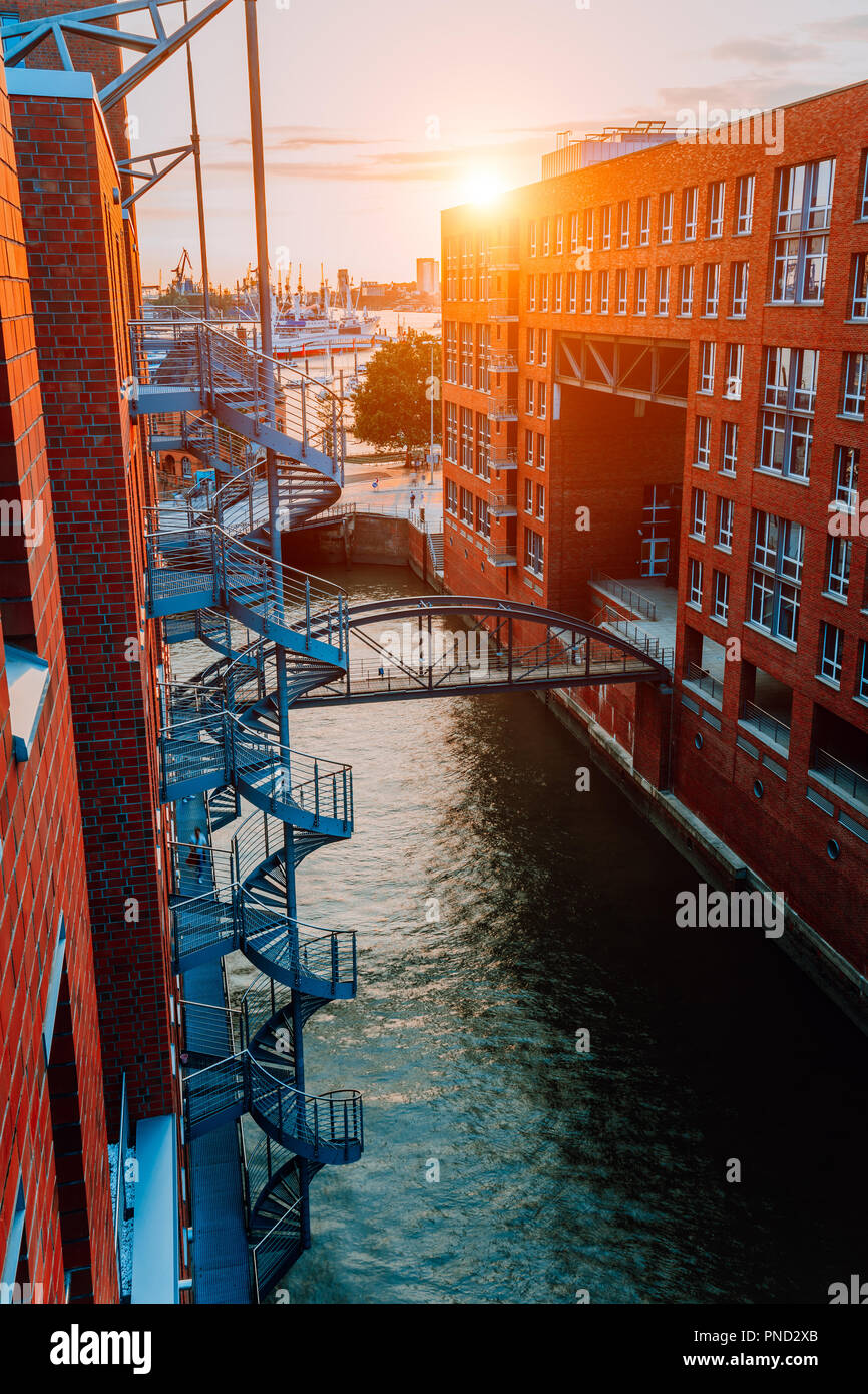 Circular staircase, bridge over canal and red brick buildings in the old warehouse district Speicherstadt in Hamburg in golden hour sunset light, Germany. View from above Stock Photo