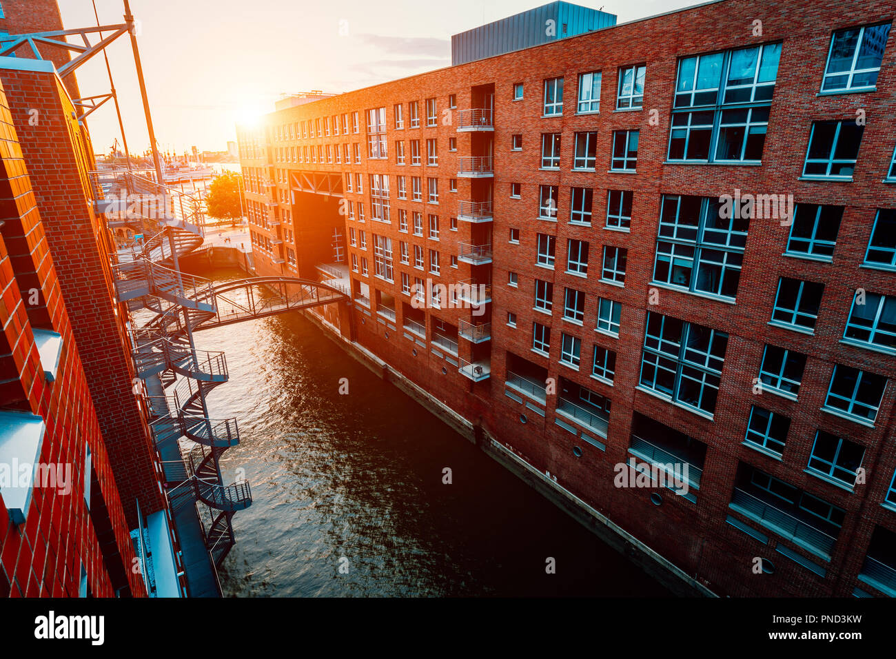 HafenCity canal. Circular staircase, bridge over canal and red brick buildings in the old warehouse district Speicherstadt in Hamburg in golden hour sunset light, Germany. View from above Stock Photo