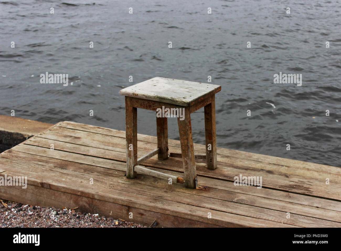 old wooden stool stands on the shore of Lake Ladoga Stock Photo