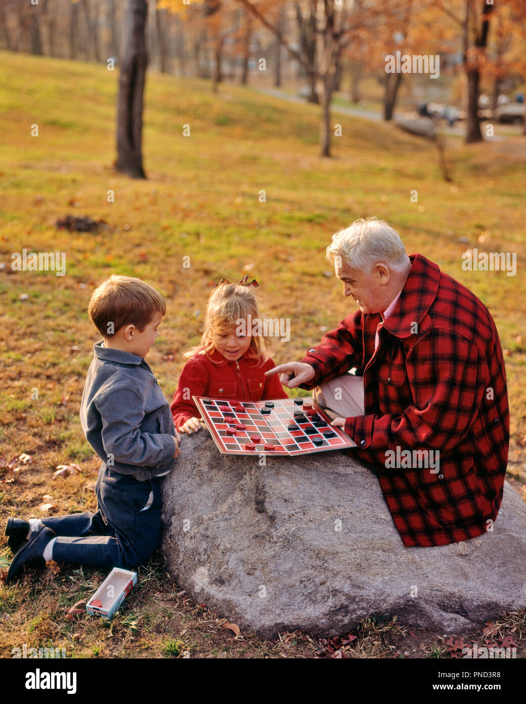 1970s GRANDFATHER PLAYING CHECKERS WITH GRANDSON AND GRANDDAUGHTER AUTUMN PARK - kj5111 PHT001 HARS OLD FASHION SISTER 1 JUVENILE BLOND TEAMWORK COMPETITION GRANDFATHER GRANDPARENTS JOY LIFESTYLE FEMALES GRANDPARENT BROTHERS RURAL HOME LIFE WOOL COPY SPACE FULL-LENGTH INSPIRATION CARING MALES SIBLINGS CONFIDENCE SENIOR MAN SISTERS SENIOR ADULT CHECKERS MIDDLE-AGED MIDDLE-AGED MAN HAPPINESS LEISURE AND CHOICE EXCITEMENT KNOWLEDGE RECREATION AUTHORITY SIBLING CONNECTION GRANDDAUGHTER GRANDFATHERS GRANDSON CHECKERBOARD GRAY JUVENILES RELAXATION TOGETHERNESS WOODLAND CAUCASIAN ETHNICITY GRANDPA Stock Photo