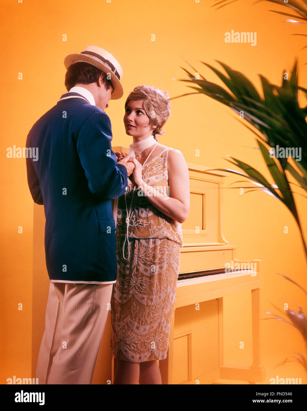 1970s COUPLE MAN WOMAN WEARING 1920s ERA JAZZ AGE CLOTHES HOLDING HANDS STANDING BY PAINTED YELLOW UPRIGHT PIANO  - ks8928 PHT001 HARS AGE COLOR STRAW OLD TIME NOSTALGIA OLD FASHION 1 STYLE COMMUNICATION BLOND YOUNG ADULT SEXY TEAMWORK STRONG COSTUMES JOY LIFESTYLE ACTOR FEMALES MARRIED SPOUSE HUSBANDS HOME LIFE FRIENDSHIP FULL-LENGTH HALF-LENGTH LADIES PERSONS INSPIRATION CARING CHARACTER MALES BLAZER ENTERTAINMENT PERFORMING ARTS UPRIGHT HAPPINESS JAZZ LEISURE PERFORMER STYLES MELODRAMA CHARACTERS CHOICE EXCITEMENT BY ENTERTAINER PAINTED CONNECTION ACTORS DRAMA STYLISH PERSONAL ATTACHMENT Stock Photo