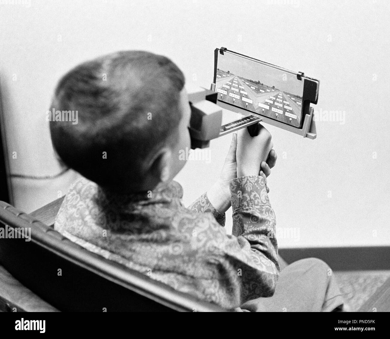1960s BOY DOING REMEDIAL READING FOR AN EYE DEFECT USING A LENTICULAR STEREOSCOPE - m8076 HAR001 HARS MUSCLES OPTICS PERCEPTION READER IMAGES BACK VIEW DEVICE GROWTH JUVENILES PRE-TEEN PRE-TEEN BOY STEREOSCOPE BLACK AND WHITE CAUCASIAN ETHNICITY HAR001 OLD FASHIONED OLIVER WENDELL HOLMES PERSPECTIVE Stock Photo