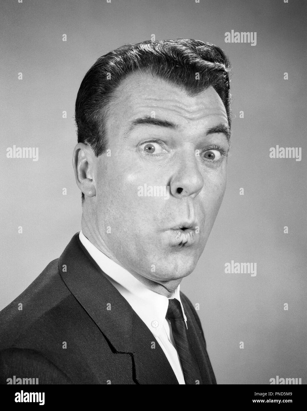 1950s 1960s MAN LOOKING AT CAMERA WITH EYES WIDE LIPS PURSED SURPRISED SHOCKED FACIAL EXPRESSION WHISTLING  - p7021 HAR001 HARS AMAZED B&W WIDE EYE CONTACT BRUNETTE AWE WEIRD HEAD AND SHOULDERS EXCITEMENT ZANY UNCONVENTIONAL PURSED AWED IDIOSYNCRATIC AMUSING ASTONISHED ECCENTRIC EYES WIDE OPEN MID-ADULT MID-ADULT MAN PUCKER WOW BLACK AND WHITE CAUCASIAN ETHNICITY ERRATIC HAR001 OLD FASHIONED Stock Photo