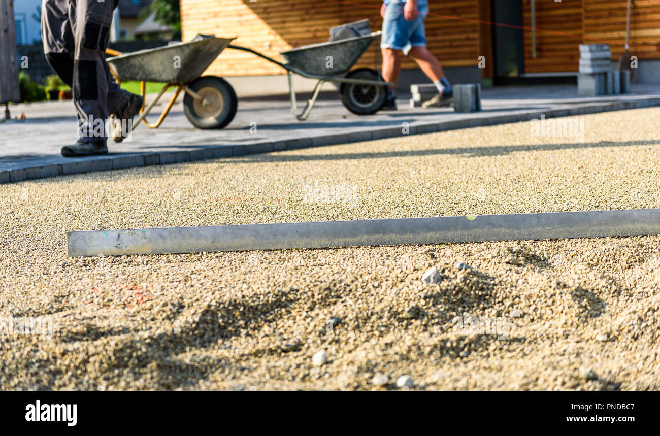 Laying gray concrete paving slabs in house courtyard driveway patio