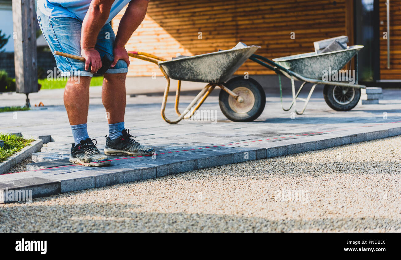 Laying gray concrete paving slabs in house courtyard driveway patio