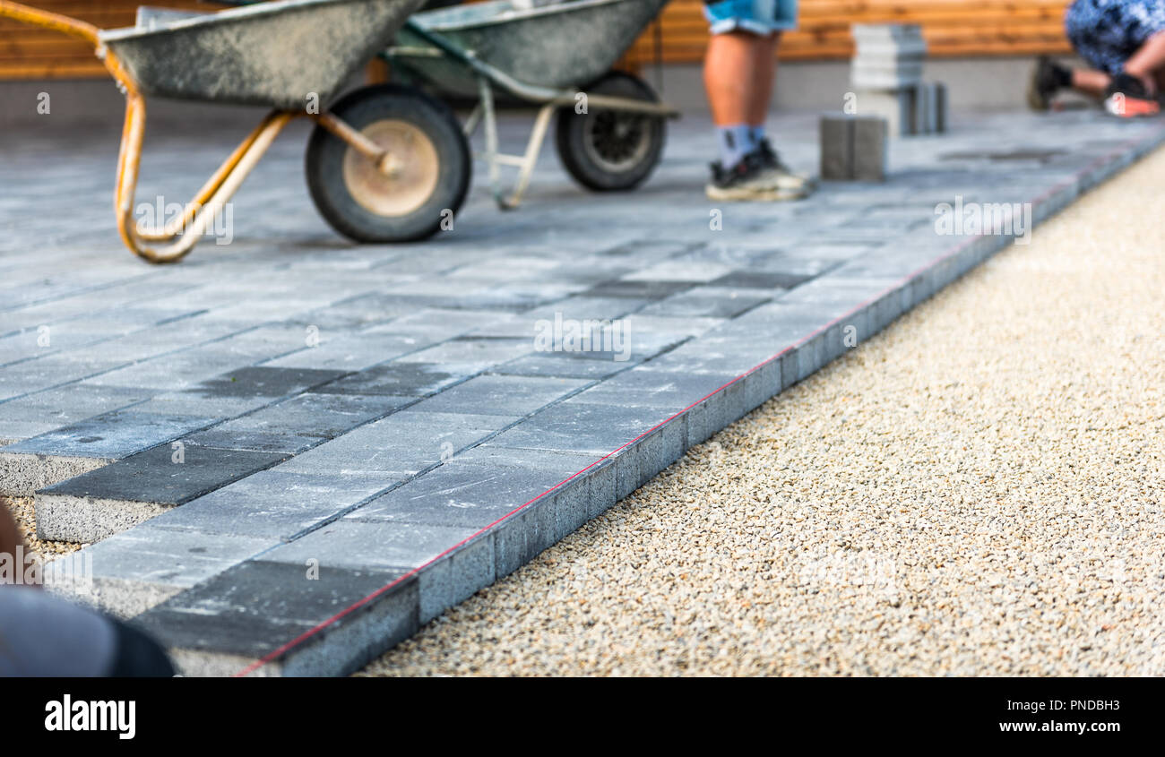 Laying gray concrete paving slabs in house courtyard driveway patio