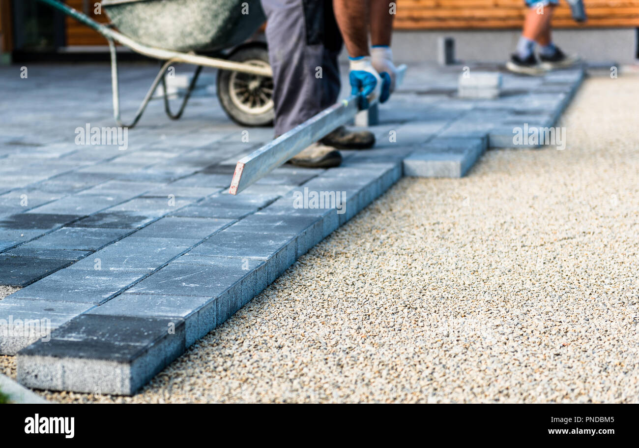 Laying gray concrete paving slabs in house courtyard driveway patio