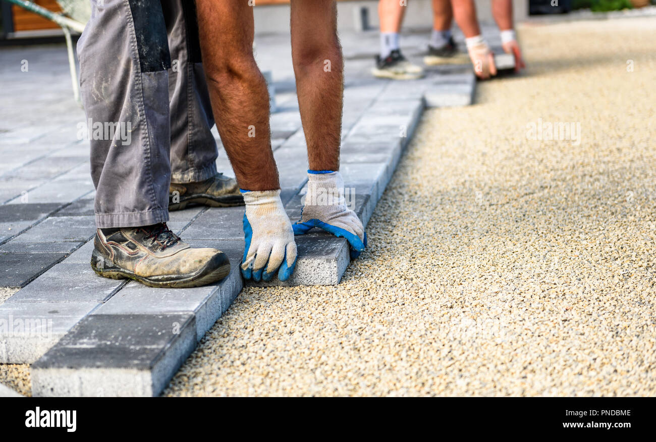 Laying gray concrete paving slabs in house courtyard driveway patio