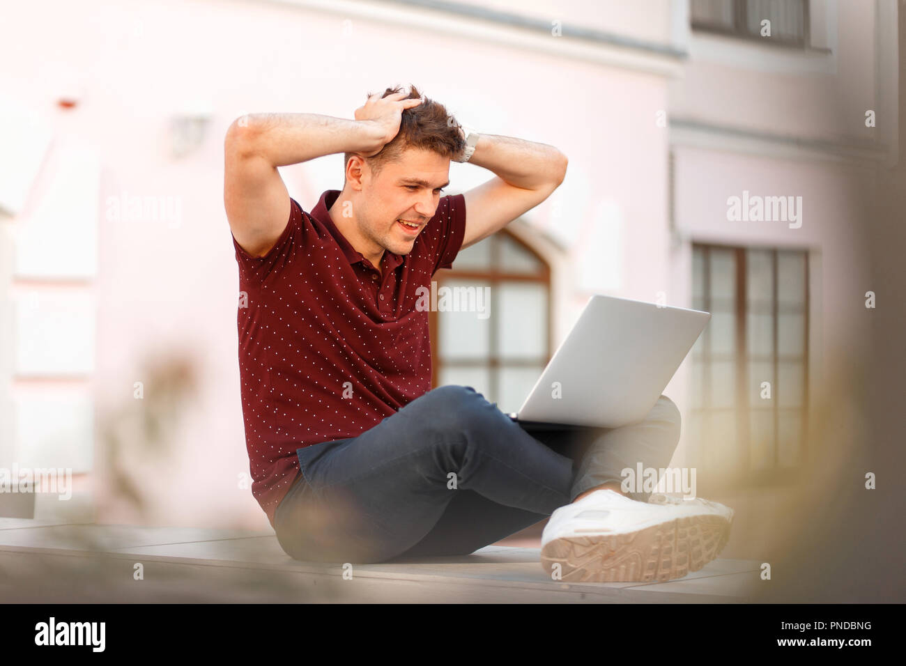 happy young businessman with a laptop enjoys the results of his work in the city. Concept of enjoy emotions Stock Photo