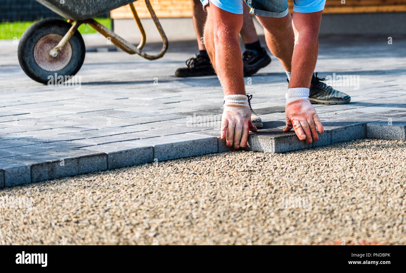 Laying gray concrete paving slabs in house courtyard driveway patio