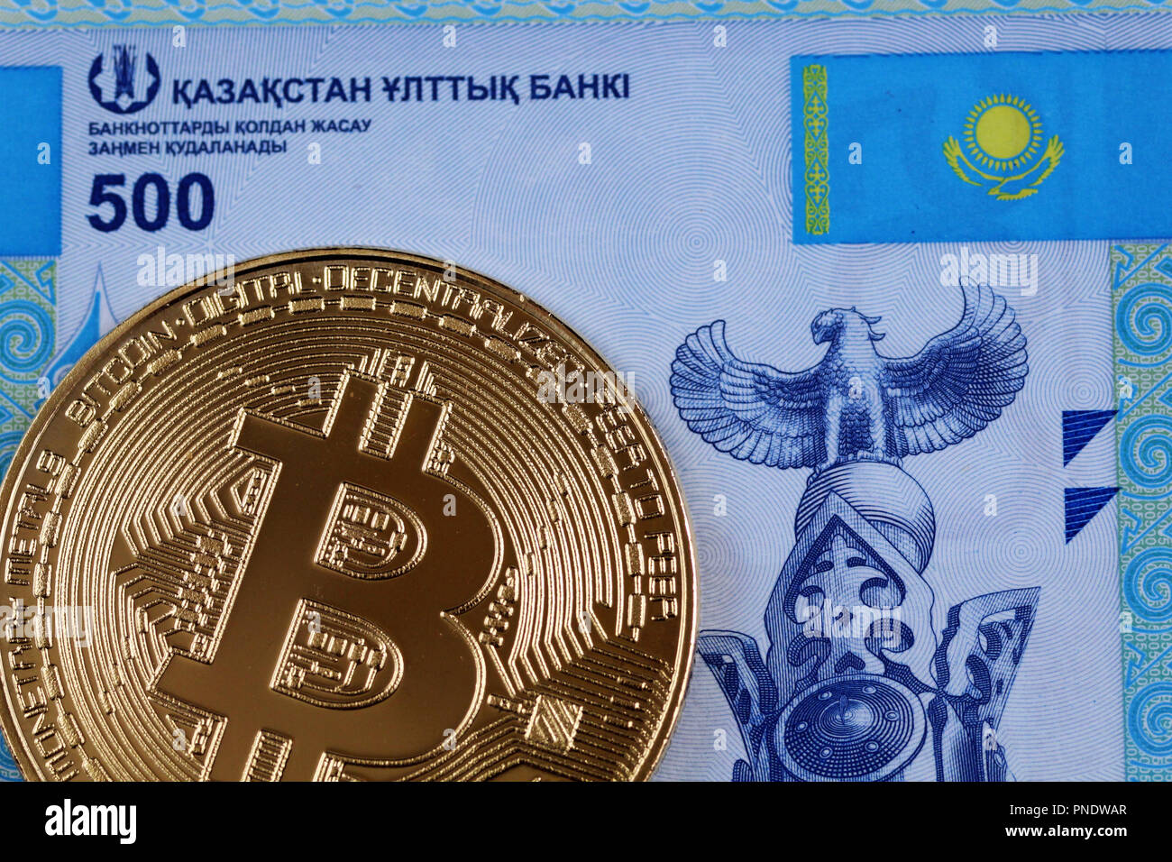 A close up image of a blue five hundred Kazakhstani tenge bill with a golden bitcoin Stock Photo