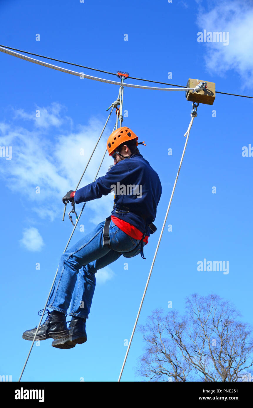Young man reaching the end of the  a zip-wire / line. Stock Photo