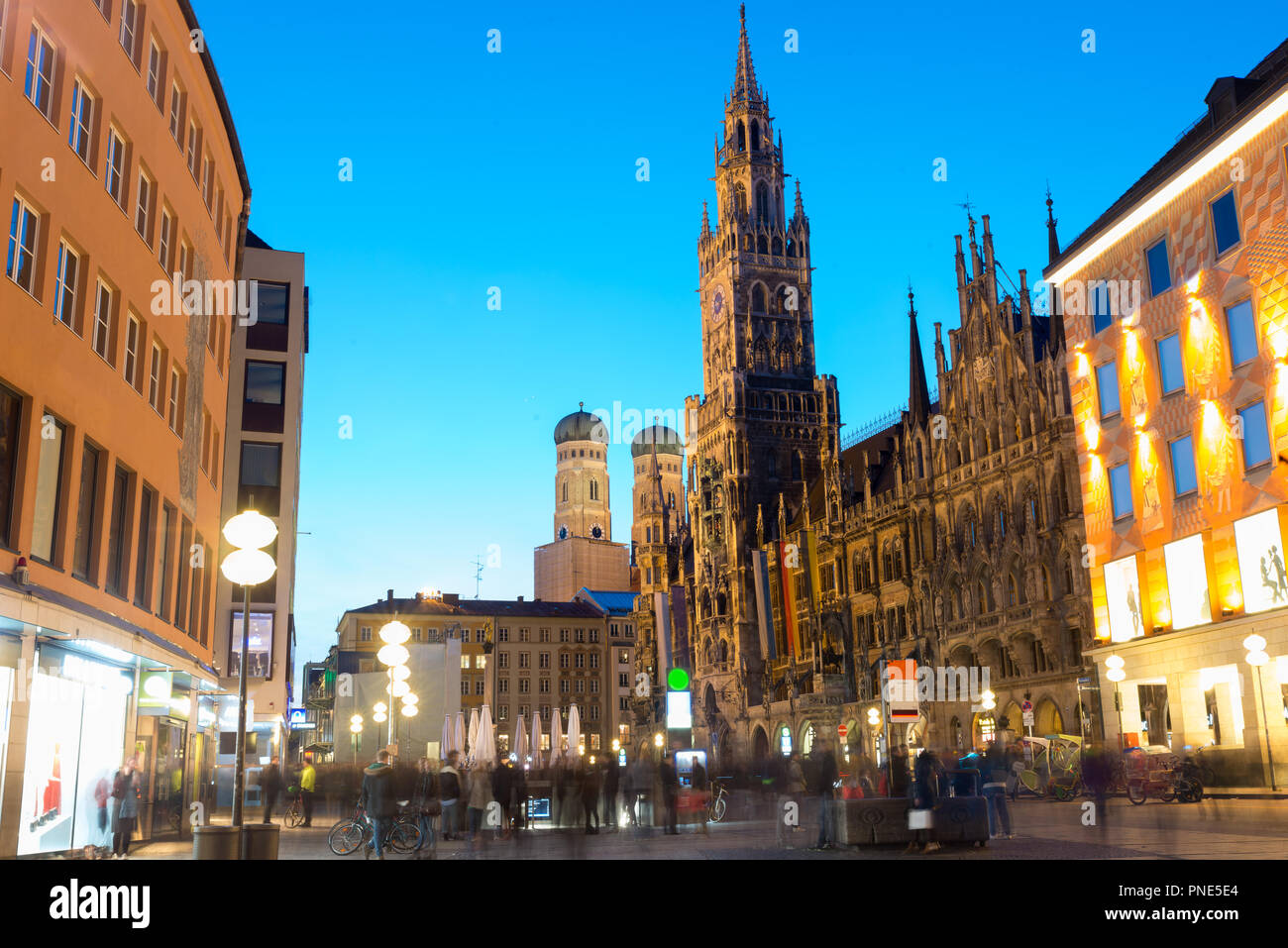 People walking at Marienplatz square and Munich city hall in night in Munich, Germany. Cafes, bars, shops and restaurants. Motion blurred people. Stock Photo