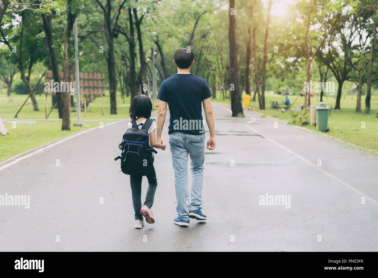Asian father hand lead his girl child in summer park go to school. Trust family and back to school concept. Stock Photo