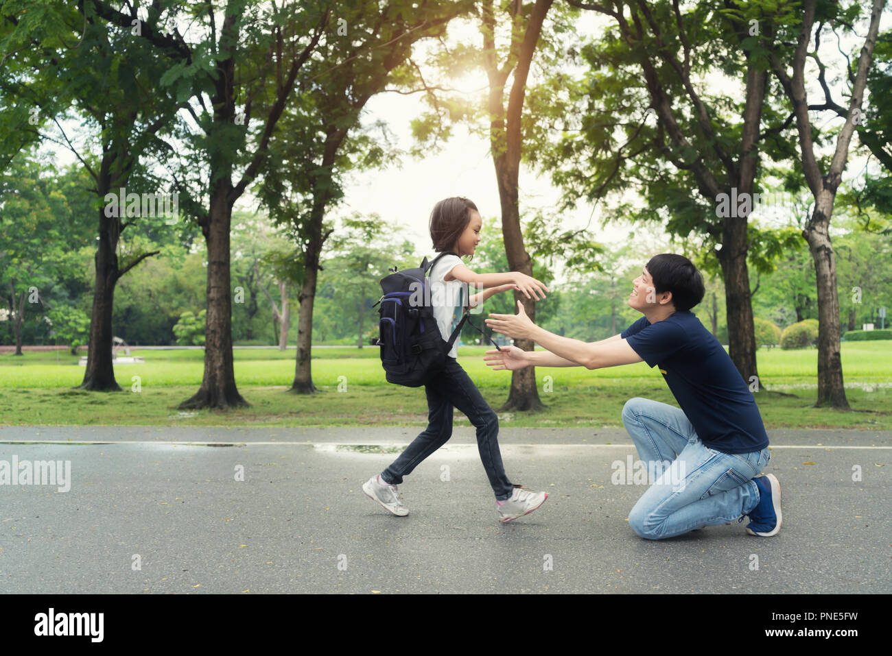 Asian girl kids student run into father hands to hug her after back to school. Pupil student. Stock Photo