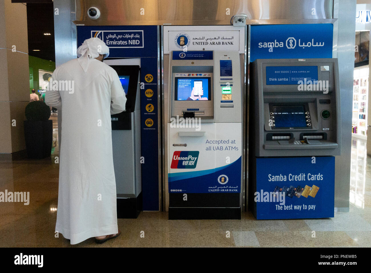 Emirati man using cash ATM machine in Dubai, UAE Stock Photo