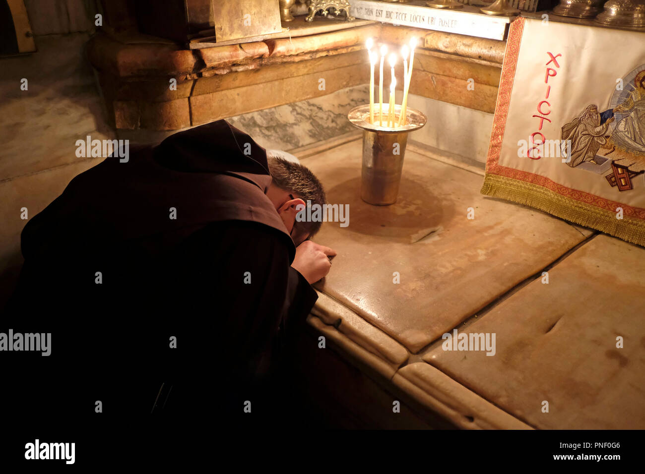 A Franciscan friar prays inside the Aedicule the14th Station of the