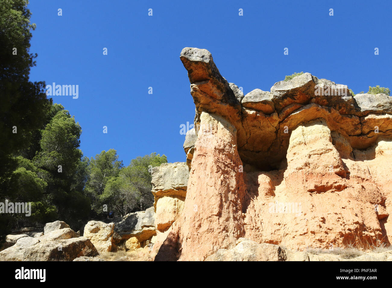 A protruding red rock with trees and a deep blue sky in the canyon style hills of Anento, a small town in Aragon, Spain Stock Photo