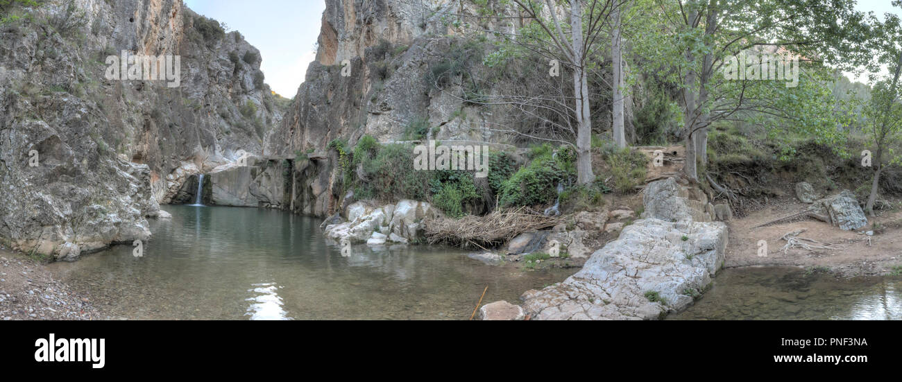 A rural landscape of a small lake and Aguavivas river waterfalls inside a rocky canyon dug by the water, and a stone bridge, at the sunset, in Spain Stock Photo