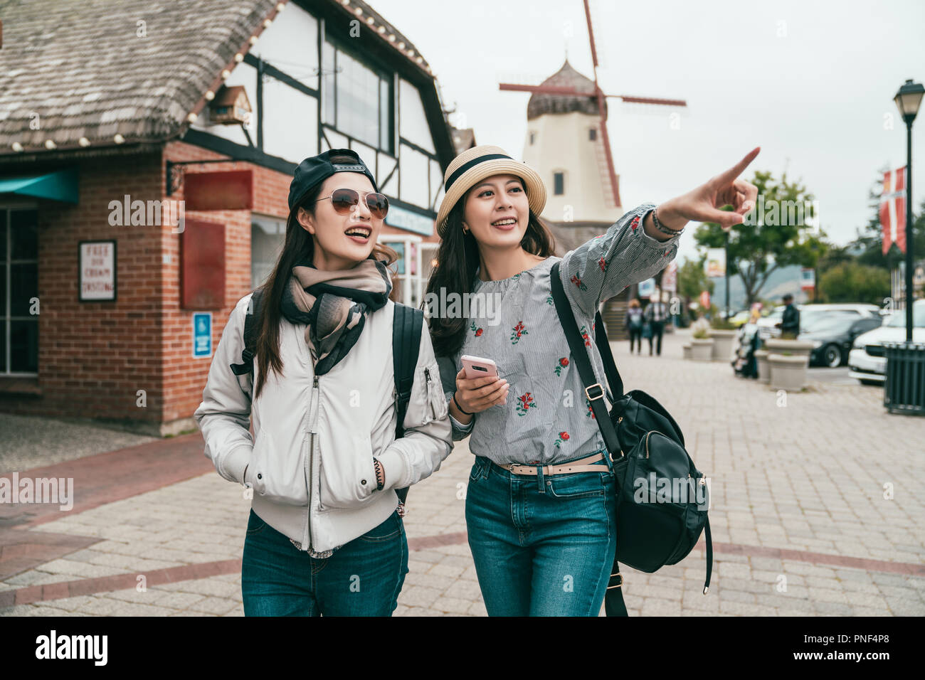 young sisters traveling together in a old town and one is pointing to somewhere ahead joyfully. Stock Photo