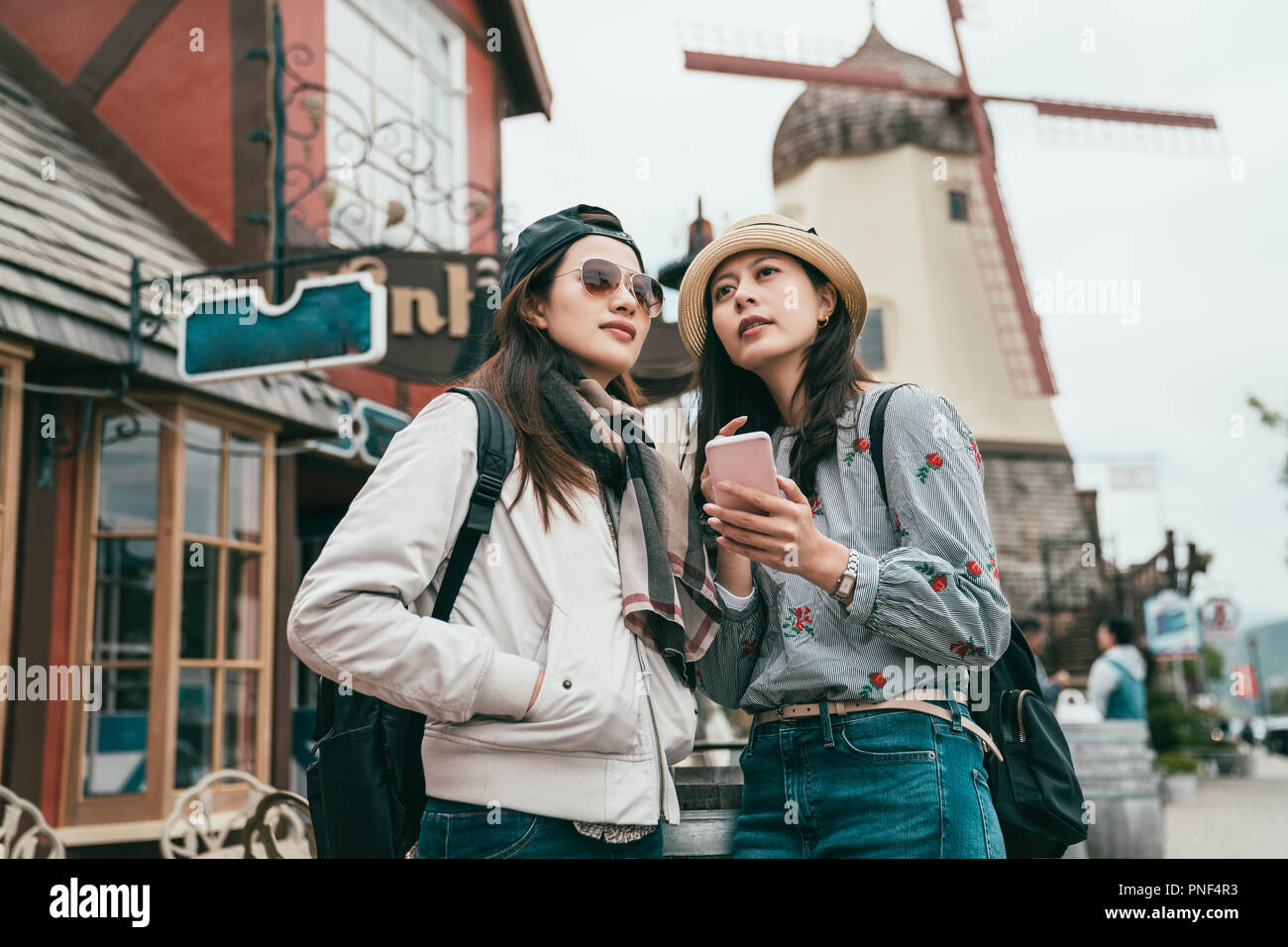 two good friends standing in the street and one holding a smartphone to check around. Stock Photo