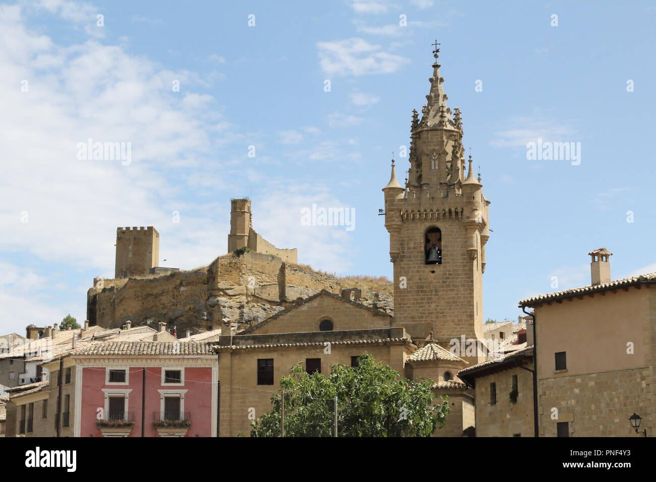 The brick made Holy Mary Church (Iglesia de Santa Maria) with its bell tower and the old rumbled castle of Uncastillo, a rural town in Spain Stock Photo