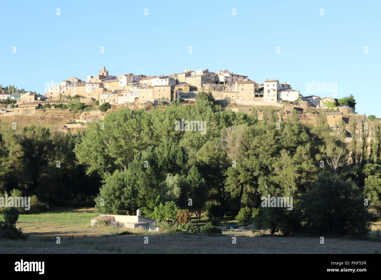 A landscape at sunset of Frago, a traditional Aragonese town over a hill surrounded by cultivated fields, firs and the typical Mediterranean forest Stock Photo