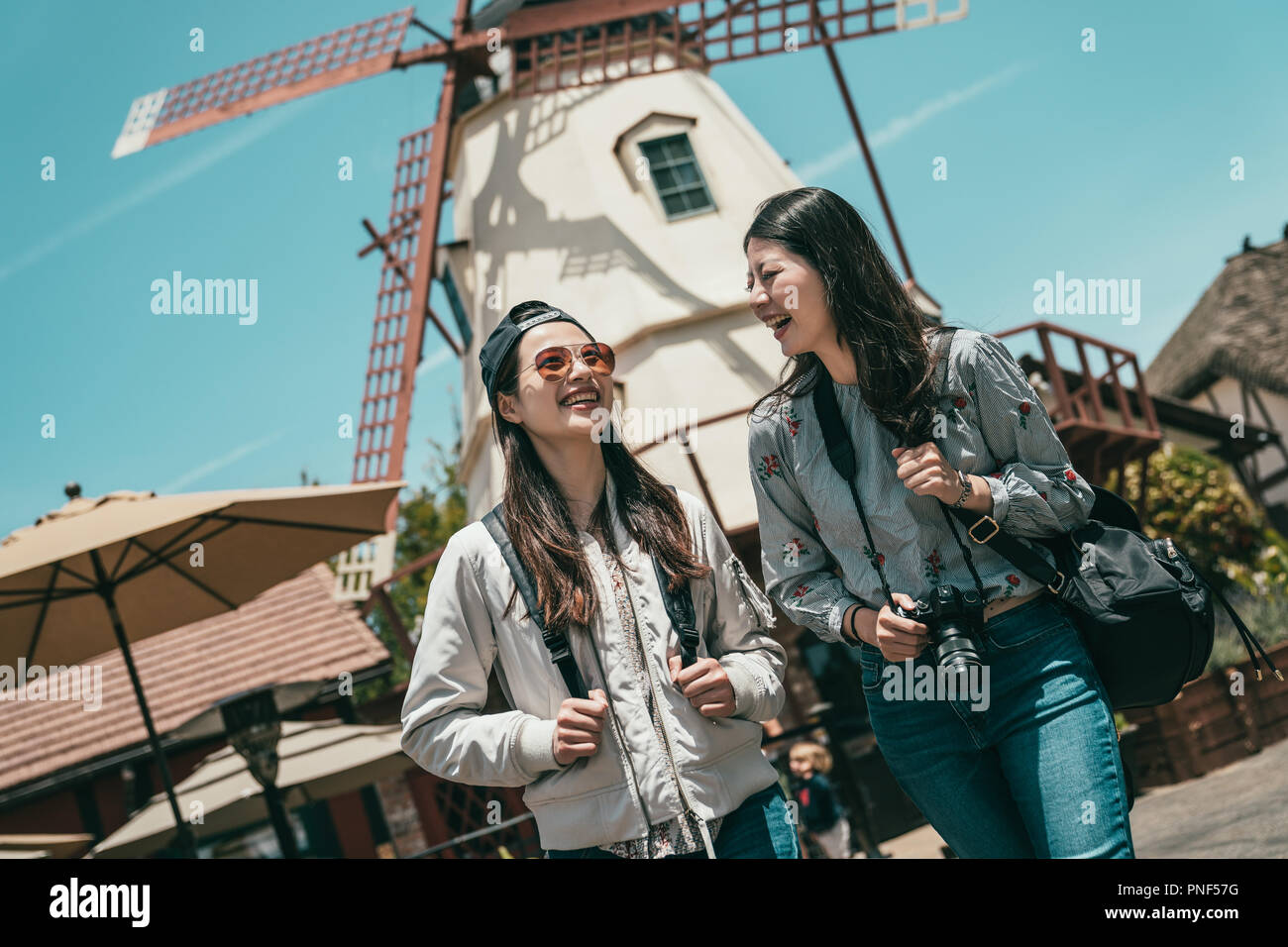 friends talking happily while sightseeing in a lovely town with a background of windmill amd houses. Stock Photo