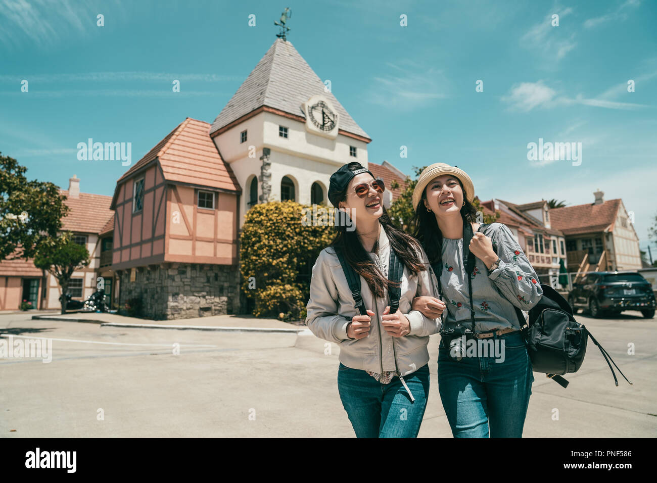 two beautiful women sightseeing and walking in a space in fornt of a beautiful and traditional architecture. Stock Photo