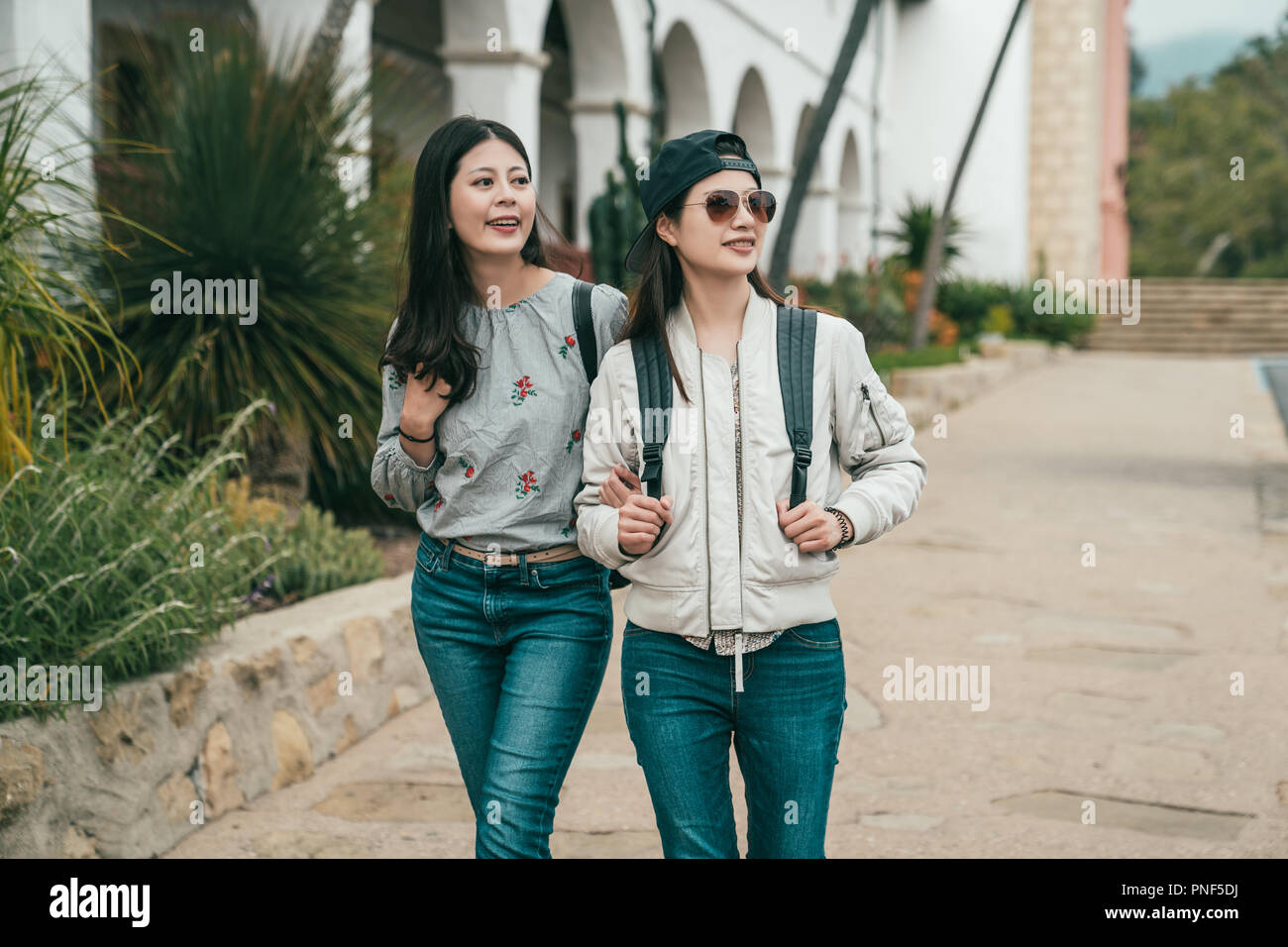 young beautiful friends walking in the sidewalk and feeling cheerful and relaxed while sightseeing. Stock Photo