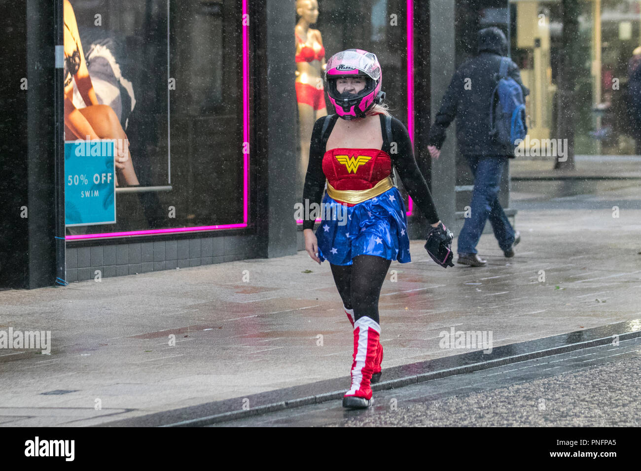 Woman wearing Classic Supergirl (Wonderwoman) teenage costume in Preston, Lancashire. Sept 2018. UK Weather: Blustery heavy showers in the city centre. Credit; MediaWorldImages/AlamyLiveNews Stock Photo