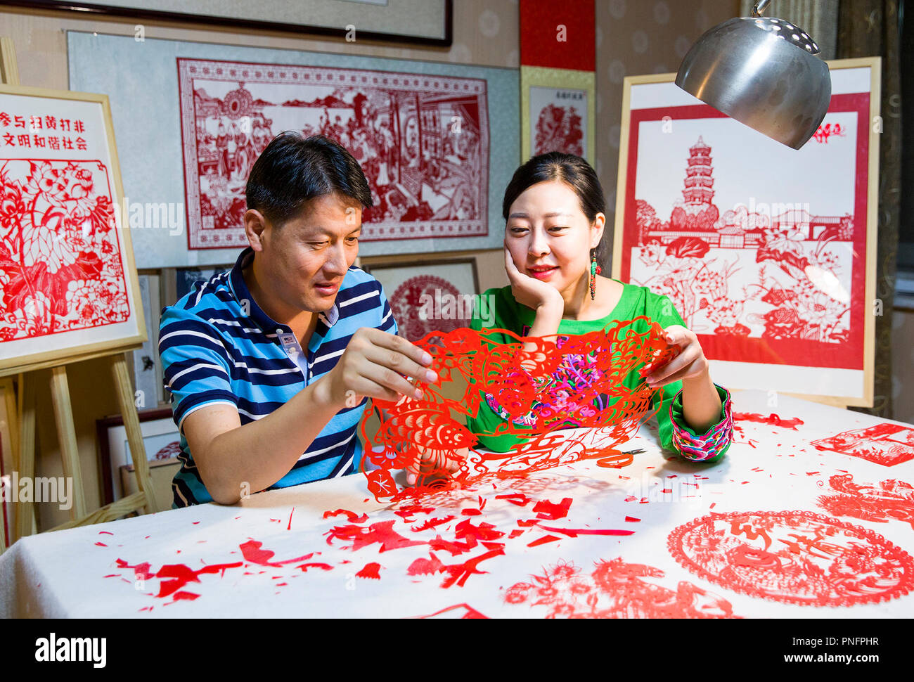 (180921) -- TENGZHOU, Sept. 21, 2018 (Xinhua) -- Papercutting artist Qiu Ting and her husband Qiu Hanping look at a harvest-themed papercutting at home in Tengzhou City, east China's Shandong Province, Sept. 17, 2018. Qiu spent over two months in creating a 2,018-centimeter-long papercutting to greet the first Chinese farmers' harvest festival, which falls on the Autumnal Equinox, or Sept. 23 this year. (Xinhua/Song Haicun) (hxy) Stock Photo