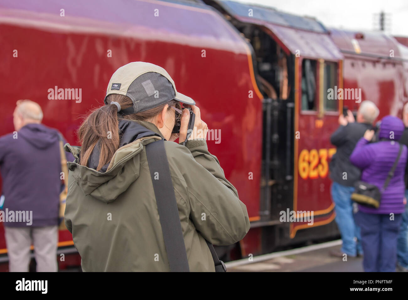 Kidderminster, UK. 21st September, 2018. Day Two of Severn Valley Railway's Autumn Steam Gala sees excited trainspotters flocking to the platform at Kidderminster SVR vintage station. Despite the rain showers, train enthusiasts take every opportunity to get as close as they can to these magnificent UK steam locomotives, particularly the Duchess of Sutherland looking resplendent in her fine crimson livery. A female photographer (rear view) is seen taking photographs of the busy platform scene at this heritage railway. Credit: Lee Hudson/Alamy Live News Stock Photo