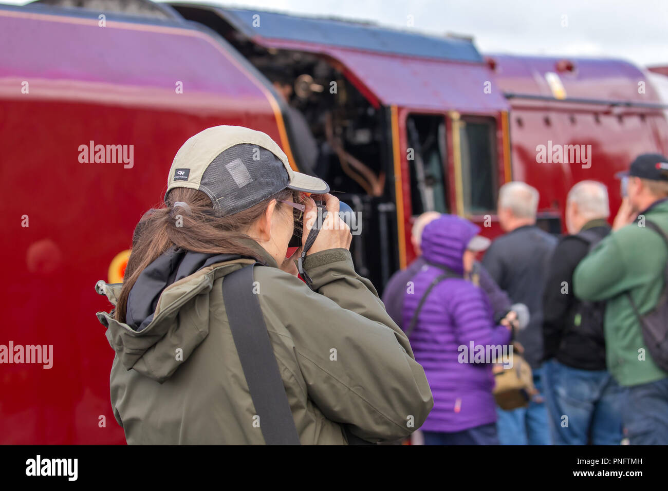 Kidderminster, UK. 21st September, 2018. Day Two of Severn Valley Railway's Autumn Steam Gala sees excited trainspotters flocking to the platform at Kidderminster SVR vintage station. Despite the rain showers, train enthusiasts take every opportunity to get as close as they can to these magnificent UK steam locomotives, particularly the Duchess of Sutherland looking resplendent in her fine crimson livery. A female photographer (rear view) is seen taking photographs of the busy platform scene at this heritage railway. Credit: Lee Hudson/Alamy Live News Stock Photo